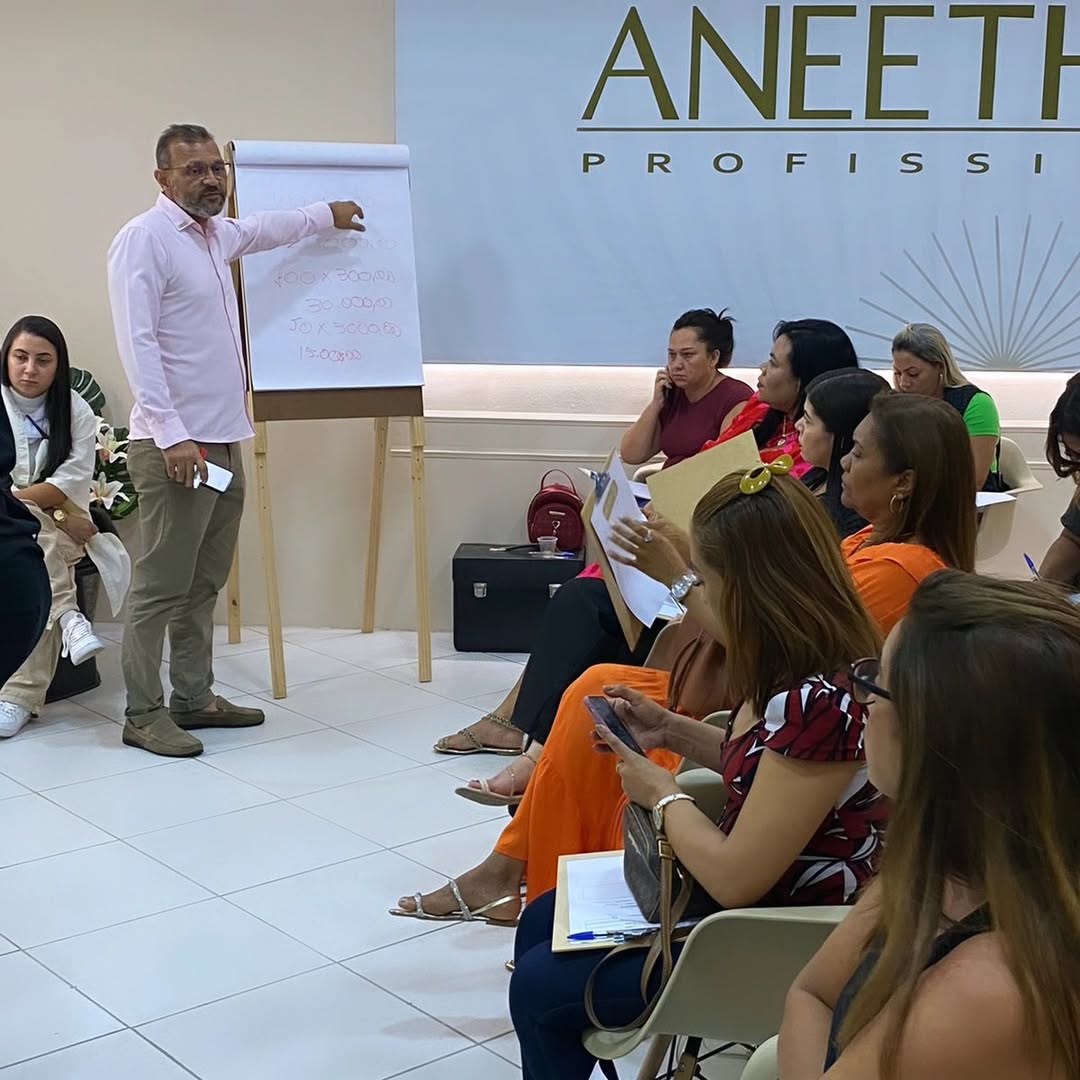 Aula presencial com flip chart mostrando cálculo de faturamento para donos de salão